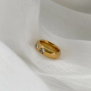 Gros plan d'une bague dorée épaisse sertie de zircons ronds et carrés sur soie