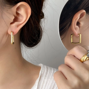 Détail de boucles d'oreilles dorées géométriques avec une bague texturée dorée