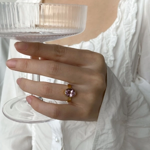 Détail d'une bague dorée minimaliste avec zircon rose ovale portée par un mannequin