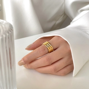 Détail d'une bague dorée à trois rangs avec trois oxydes de zirconium sur la main d'un mannequin