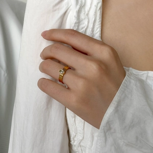 Détail de bague dorée avec anneau triple ligne et zircon ovale sur fond de tissu blanc
