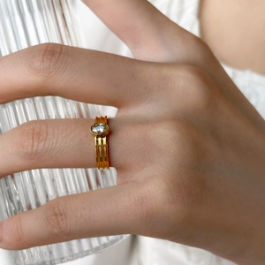 Vue détaillée d'une bague dorée avec zircon ovale portée avec un verre texturé