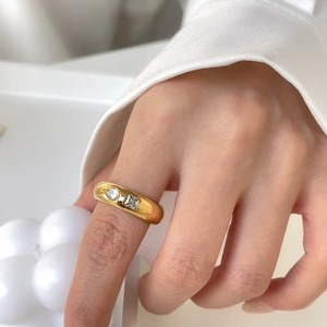Gros plan d'une bague dorée avec zircons ronds et carrés portée au doigt