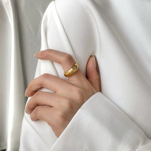 Bague large dorée tendance ornée de zircons brillants portée à la main par une femme