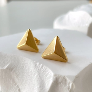 Macro shot of gold-plated geometric triangle earrings with a brushed matte texture