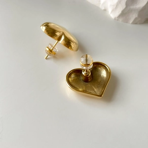 Detailed view of heart-shaped gold earrings with secure silicone plug backings