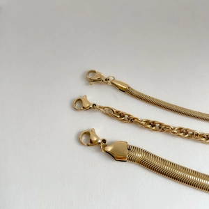 Detail of three minimalist gold snake and link chains with secure lobster clasps