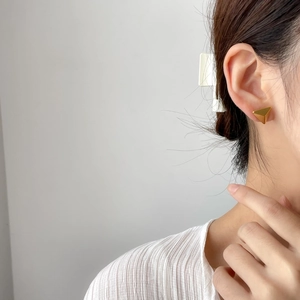 Detailed view of minimalist gold triangle stud earring worn on ear for modern styling