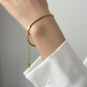 Detail of a minimalist gold flat snake chain bracelet with an adjustable link on wrist