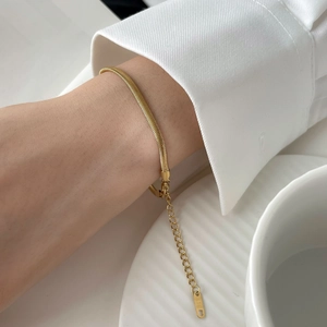 Macro shot of gold flat snake chain bracelet with K18 engraving on extension tag