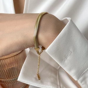 Detailed view of a gold flat snake chain bracelet with adjustable extender on wrist