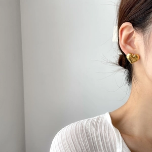 Polished gold heart studs worn by a model to show elegant style and metallic luster