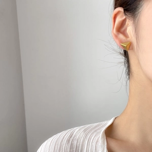 Minimalist gold geometric triangle stud earrings for women shown on a model side view