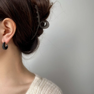 Détail d'une boucle d'oreille créole torsadée noire et d'une pince à cheveux mate