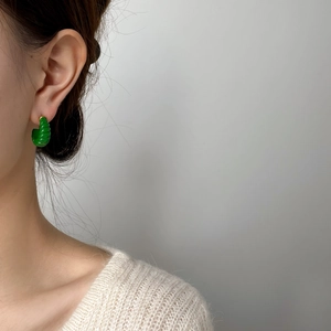 Détail de créoles en C vert vif avec texture spirale portées par un modèle