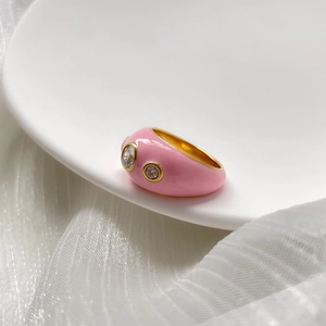 Détail d'une bague en émail rose avec zircons sur assiette en céramique blanche