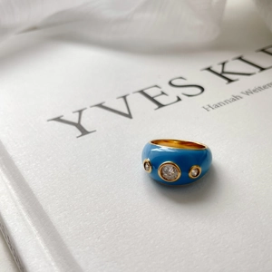 Détail d'une bague dorée avec émail bleu et pierres de zircone scintillantes