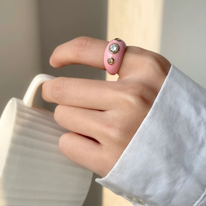Détail d'une bague en émail rose avec zircons étincelants portée par un modèle