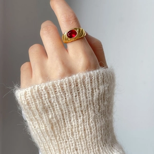 Nahaufnahme eines goldenen Vintage-Rings mit rotem ovalem Edelstein und Texturband