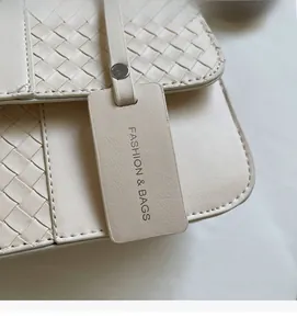 Detail of woven beige leather texture with decorative fashion tag on a square crossbody bag
