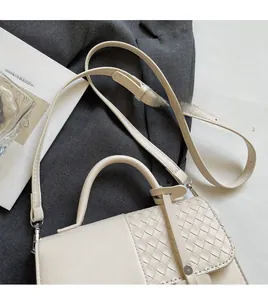 Close-up of woven leather square bag with adjustable strap and top handle design