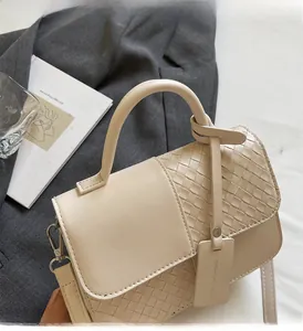 Detailed view of beige woven leather tote bag with elegant chain handle on aesthetic setting