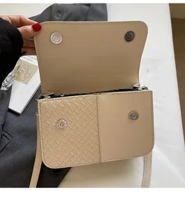 Detail of beige flap bag with woven texture, metal magnetic buckles and zip closure