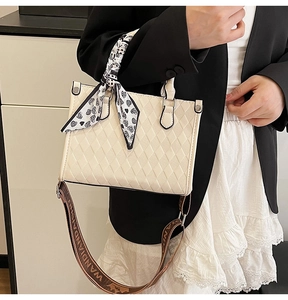 Detail of quilted tote bag with heart print scarf handle and woven strap