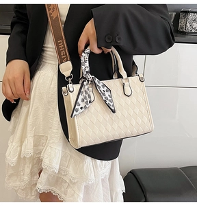 Close-up of quilted beige tote bag with heart scarf and branded wide shoulder strap