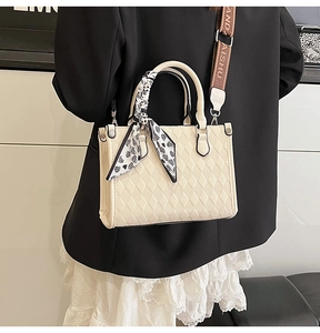 Close-up of cream quilted tote bag with floral scarf handle and wide woven strap