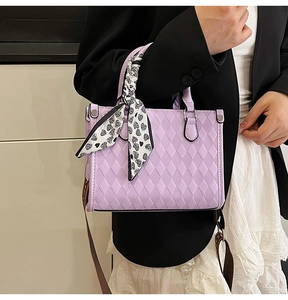 Macro detail of purple quilted handbag featuring decorative heart silk scarf on handle