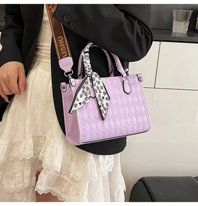 Detail of purple quilted handbag with heart pattern scarf and woven shoulder strap