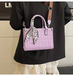 Detail of purple quilted bag with silk scarf handle and wide branded woven strap