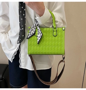 Detail of bright green quilted handbag with patterned silk scarf and printed shoulder strap