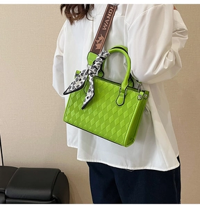 Detail of green quilted tote bag featuring patterned shoulder strap and silk scarf