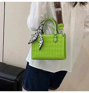 Detail of green quilted handbag with HU strap and heart silk scarf decoration