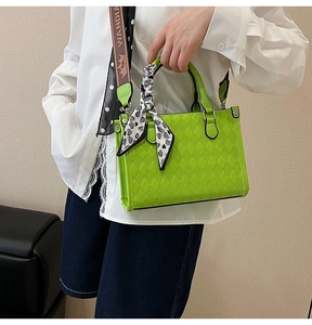 Detail of green quilted tote bag with heart scarf and woven strap on model