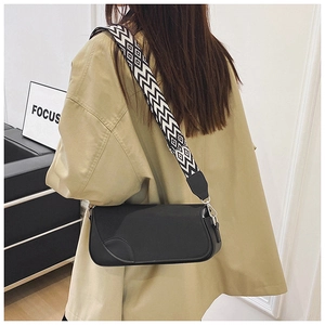 Detail of a black baguette shoulder bag featuring a wide geometric pattern woven strap