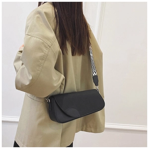Detail of minimalist black leather crossbody bag with geometric pattern wide shoulder strap