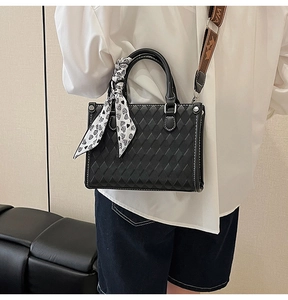 Detail of black quilted tote bag with contrast white stitching and heart pattern scarf