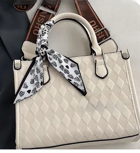 Close-up of quilted cream tote bag with silk scarf detail and brown branded strap