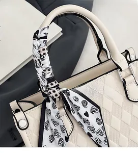 Close-up of beige quilted tote bag with silk scarf detail and black piping accents