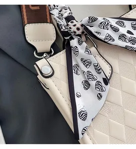 Close-up of quilted beige tote with wide brown strap and decorative zebra heart scarf