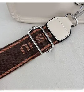 Detailed view of adjustable brown jacquard strap with silver hardware on cream tote