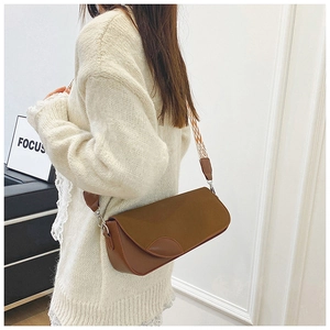 Brown vintage faux leather shoulder bag with ethnic patterned strap worn by a model