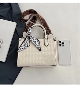 Close-up of cream quilted tote bag with silk scarf detail and jacquard logo strap