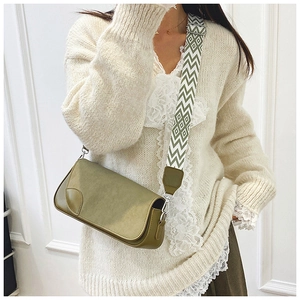 Olive green leather shoulder bag with stylish wide woven patterned strap on model