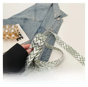 Detail of adjustable green and white geometric woven shoulder strap with silver metal buckle