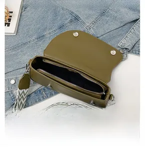 Olive green saddle bag interior view with jacquard strap on denim background