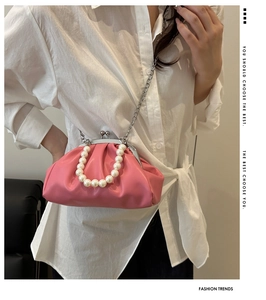 Pink pleated dumpling bag with large pearl handle and silver chain strap shown on model